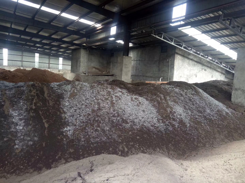 图像展示一处食用菌生产基地的工具处理区,多名工人正在将回收的白色塑料网格放入大型塑料槽中浸泡,槽内液体透明略带泡沫,旁边标有‘0.2%过氧乙酸消毒液’字样;另一侧设有晾晒架,已清洗的网格整齐摆放在上面自然风干;背景可见堆放整齐的菌袋和栽培架,整体环境整洁有序,符合卫生标准 平菇出菇网格清洗与消毒操作现场图