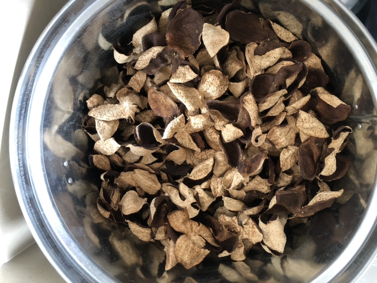 玻璃茶壶冲泡沃柑陈皮茶特写:琥珀色清亮茶汤,悬浮细小金黄色果皮碎片与微量气泡;壶旁配小碟盛放干燥沃柑陈皮片(棕褐带橙晕、表面微皱、断面显纤维纹理);背景为原木茶席与手写标签‘沃柑陈皮·6月陈’,强调实用定位而非年份炒作 沃柑陈皮茶饮成品展示