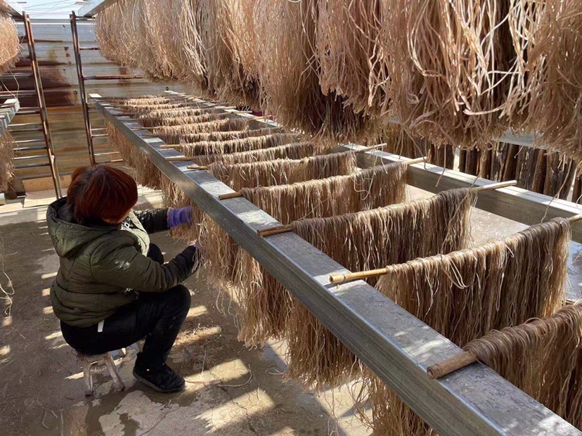 阳光下,新鲜紫薯被切成均匀薄片,整齐铺陈于传统竹编晾晒匾中;薯片表面泛着湿润光泽,边缘略显半透明,背景可见蓝天与微微晃动的竹影,体现‘当日采、当日切、当日晒’的天然工艺场景 紫薯切片在竹匾上自然晾晒的俯视特写