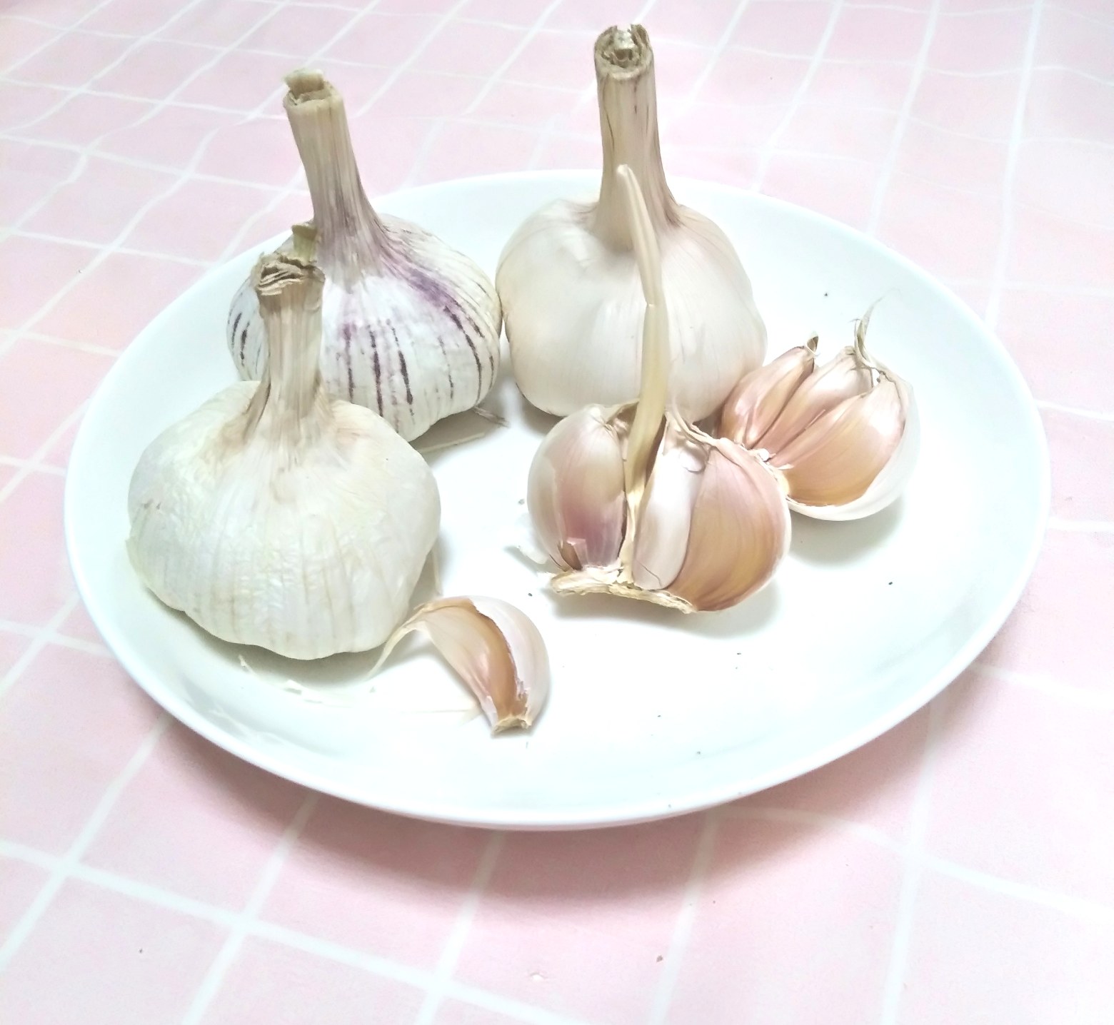 新鲜白皮蒜头摆放在木质砧板上,外皮完整洁白,蒜瓣饱满分明,旁边放有一把不锈钢小刀,准备进行剥皮处理 新鲜白皮蒜头特写,外皮洁白干燥,蒜瓣饱满未剥开,背景为木质砧板