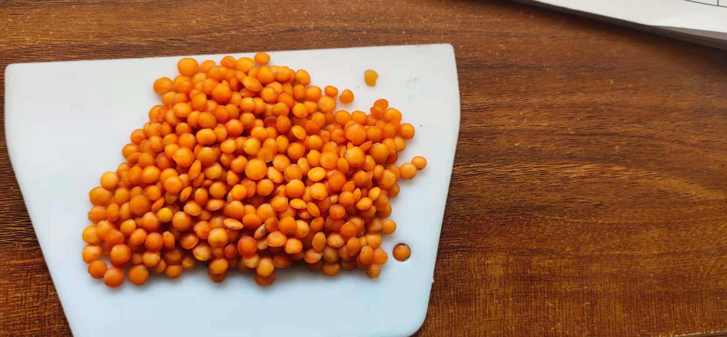 厨房场景中正在烹煮白扁豆的过程,展示从生豆到熟食的安全处理流程 厨房中正在煮沸的锅具,锅内是浸泡后的白色扁豆,水已沸腾,热气腾腾,旁边放着漏勺和干燥的白扁豆样品,背景为整洁的厨房台面
