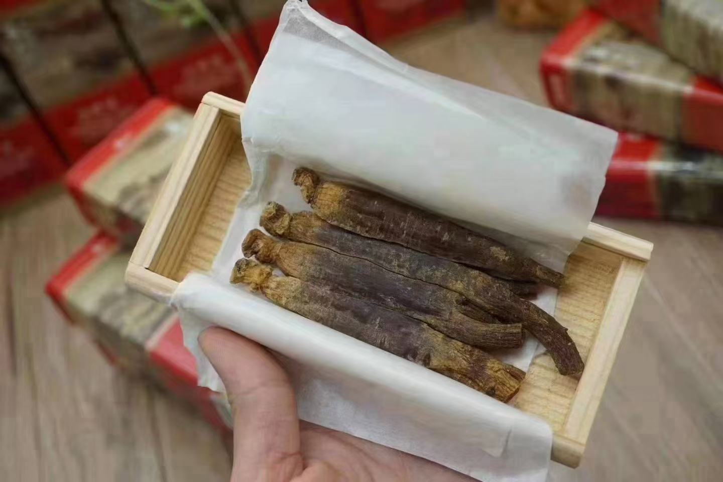 高丽参片与蜂蜜浸泡瓶装展示:透明玻璃瓶内装有淡黄色蜂蜜,其中浸泡着数片红棕色高丽参切片,背景为木质餐桌和茶具,体现自然养生氛围 高丽参片与蜂蜜浸泡瓶装展示