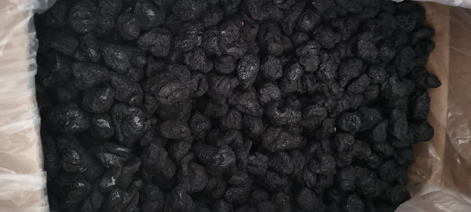 图片显示一间洁净的中药加工厂内,不锈钢高压蒸箱正打开门体,工作人员正在搬运黑色熟地黄原料,周围有温湿度监控仪器,体现现代规范化生产环境 现代化中药饮片生产车间中的熟地黄蒸制设备