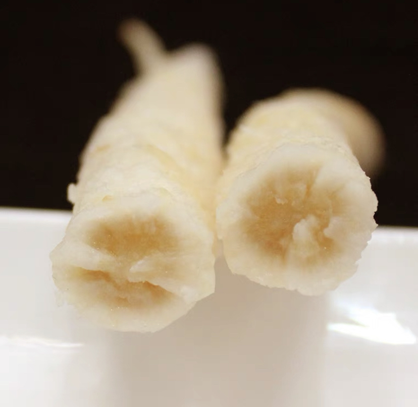 一位厨师正在将煮好的北沙参段逐个蘸入乳白色的面糊中,动作轻柔,确保每一段都均匀裹满浆液,操作台旁摆放着调料碗和沥水篮,光线明亮,突出细节操作 炸沙参面糊裹制过程