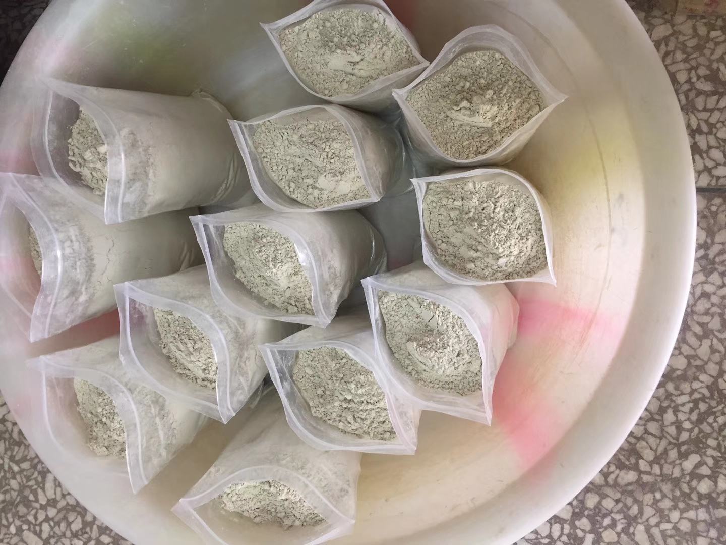 一位中年女性在厨房台面上打开一小袋冻干三七粉,将其倒入透明玻璃杯中,加入温水搅拌。旁边摆放电子秤、密封罐和产品检测报告。背景为整洁现代的家居环境,体现健康生活方式 家用冻干三七使用场景图