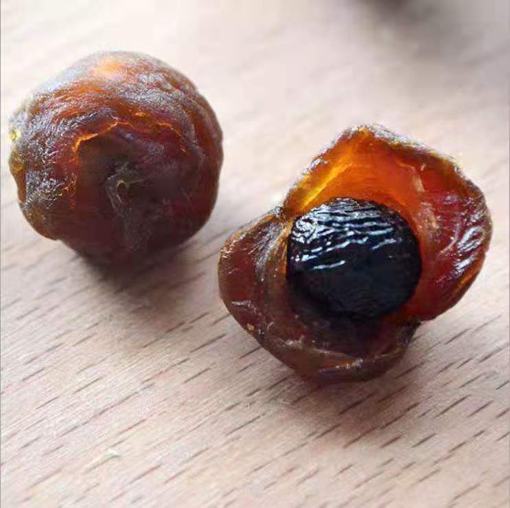 桂圆干特写：琥珀色半透明果肉堆叠在竹编簸箕上，表面微泛油润光泽，可见细密褶皱与收缩纹理