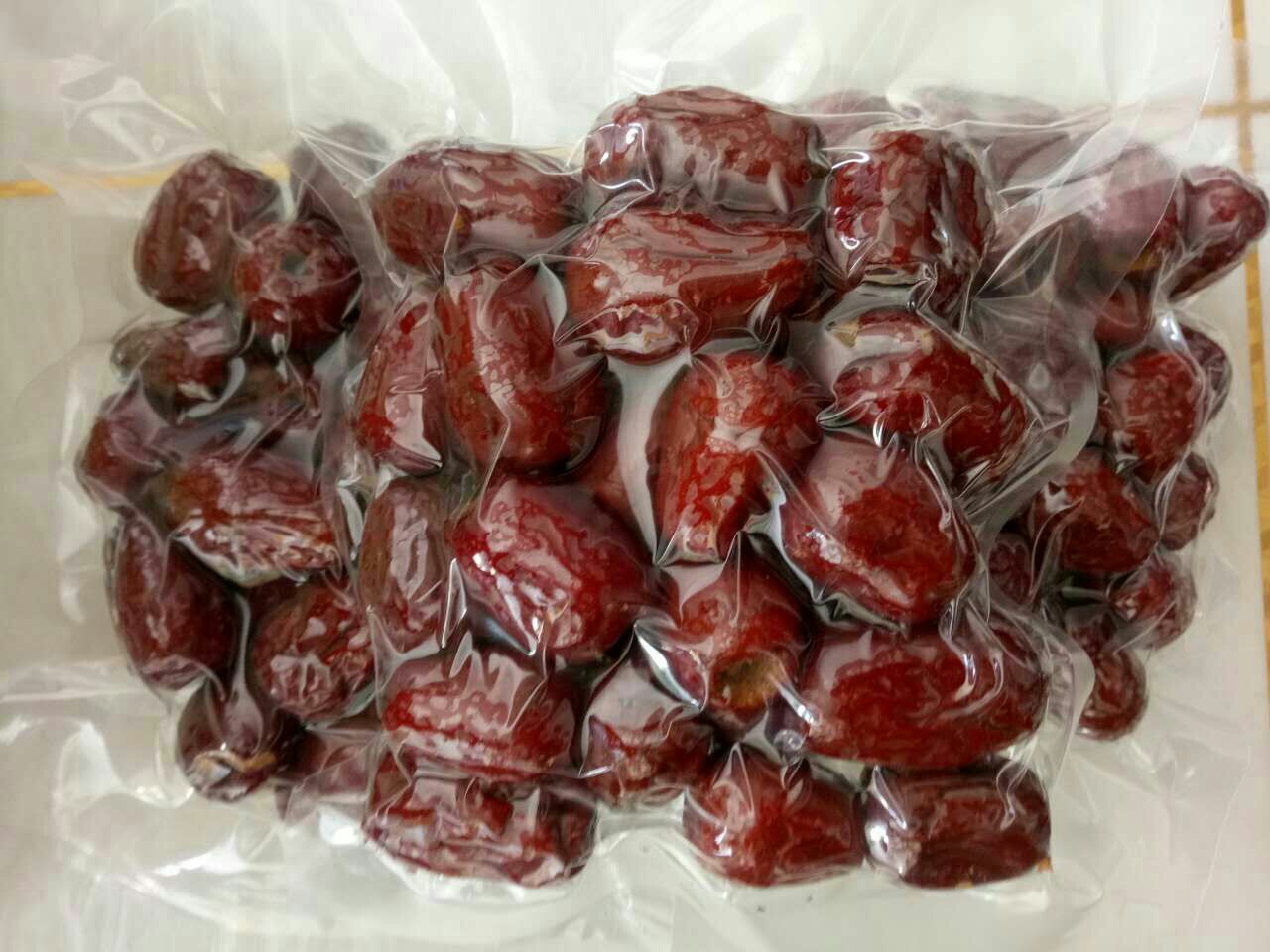 透明玻璃罐装的脆枣空心产品,金黄色泽,颗粒饱满,部分可见内部蜂窝状空心结构;旁边散落几颗掰开的样品,清晰显示内外疏松质地;背景为现代化食品加工车间,体现工业化生产标准 脆枣空心成品展示图