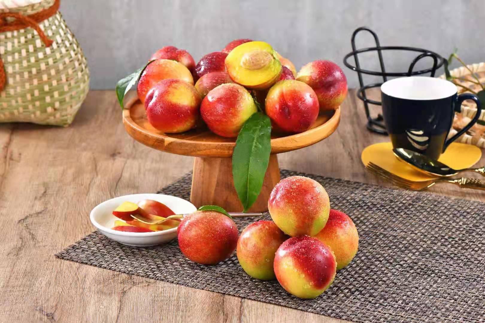 一张木质餐桌上摆放着由新鲜518油桃制作的多种美食:切片油桃摆成花朵形状、油桃酸奶杯、油桃坚果沙拉、迷你油桃果酱罐子,整体风格清新自然,适合社交媒体分享 油桃创意料理拼盘