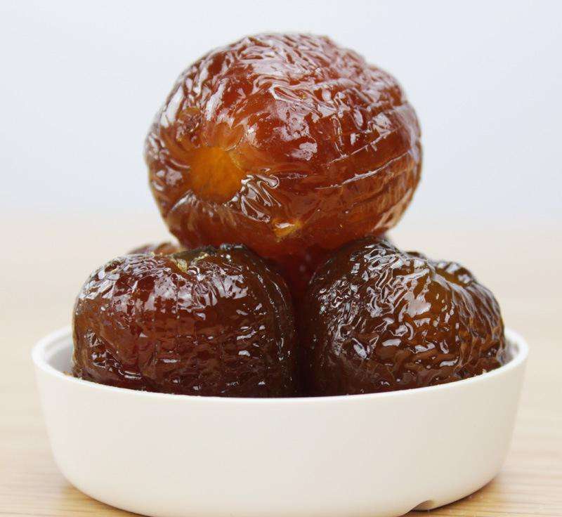 传统蜜枣制作现场,工人正在大锅中熬煮糖浆,旁边摆放着已去核的长枣原料,蒸汽弥漫,展示手工糖渍工艺流程,体现非遗技艺与食品安全可控性 蜜枣加工过程场景图