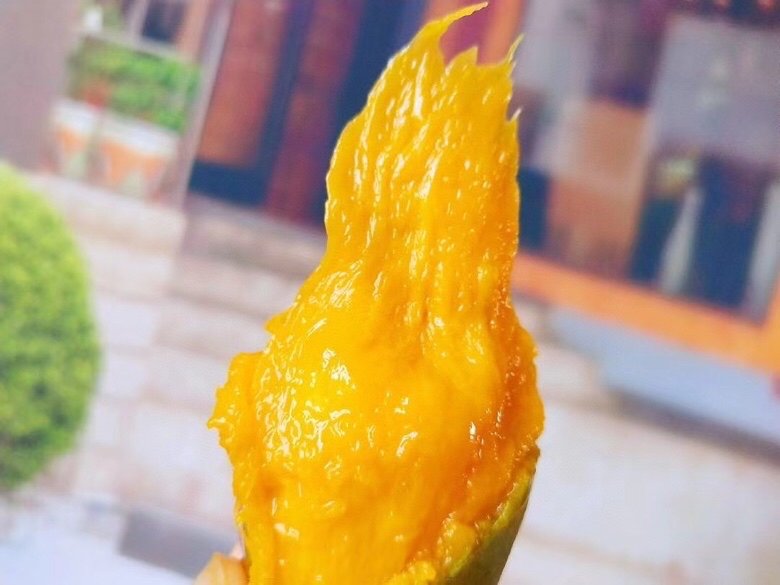 一个切开的成熟贵妃芒特写镜头,果肉呈明亮的橙黄色,汁水欲滴,果皮为红黄渐变色,果核纤薄,旁边摆放着完整的带梗果实,背景为木质餐桌,突出其新鲜与高品质 成熟贵妃芒特写展示