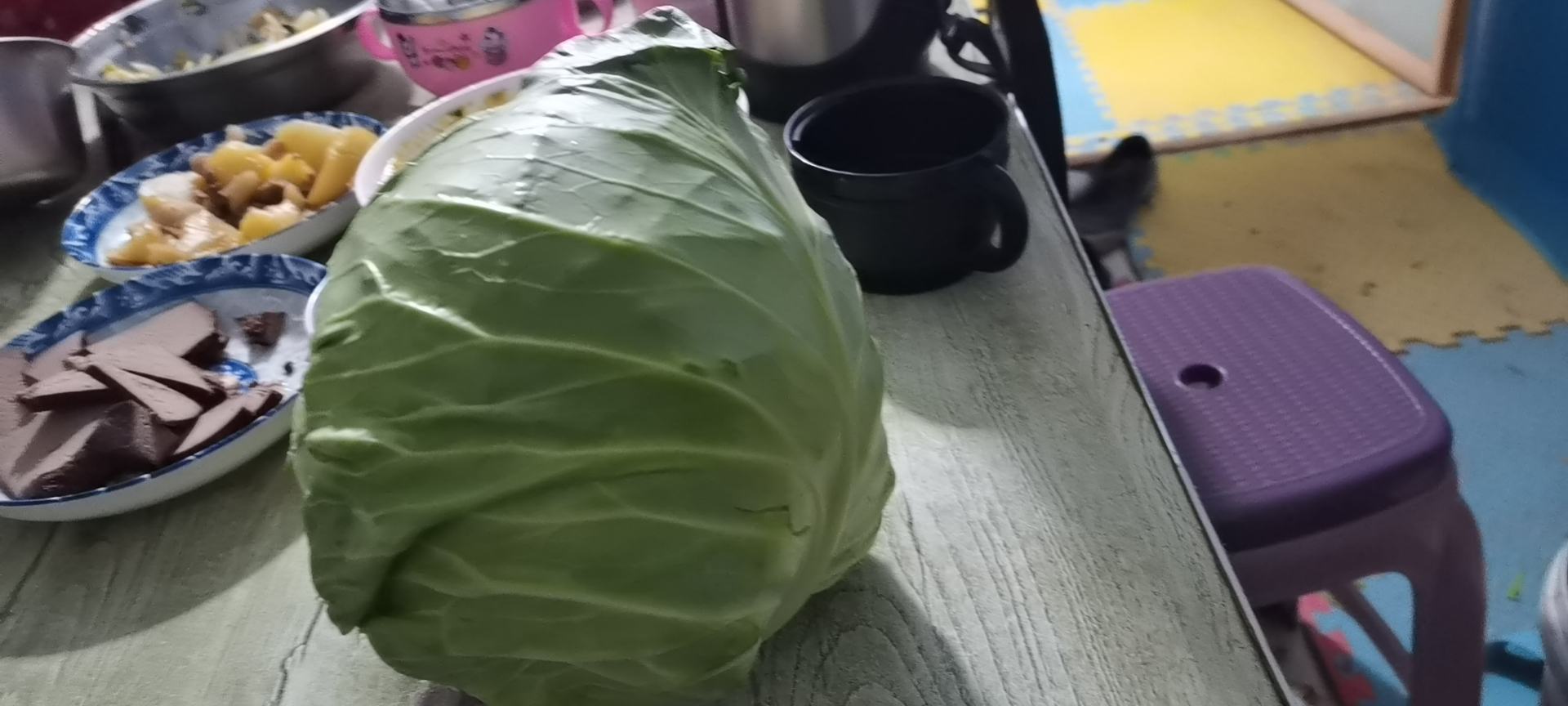 牛心甘蓝与胡萝卜、彩椒、西兰花等蔬菜一同摆放在木质餐盘中,背景为自然光线下的厨房环境 牛心甘蓝与多种蔬菜搭配摆盘的图片