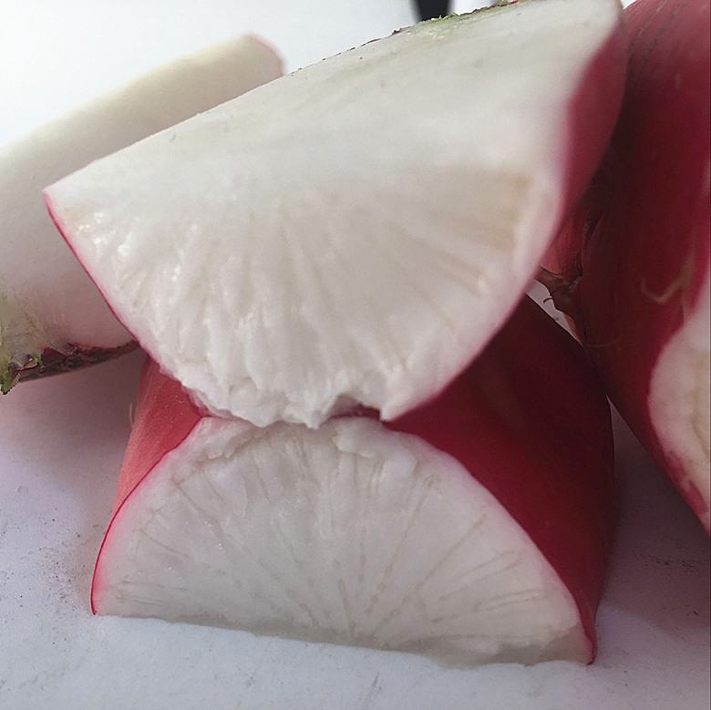 展示红皮白心萝卜的横切面,突出其红色外皮与白色内芯的对比 红皮白心萝卜切片展示内部结构