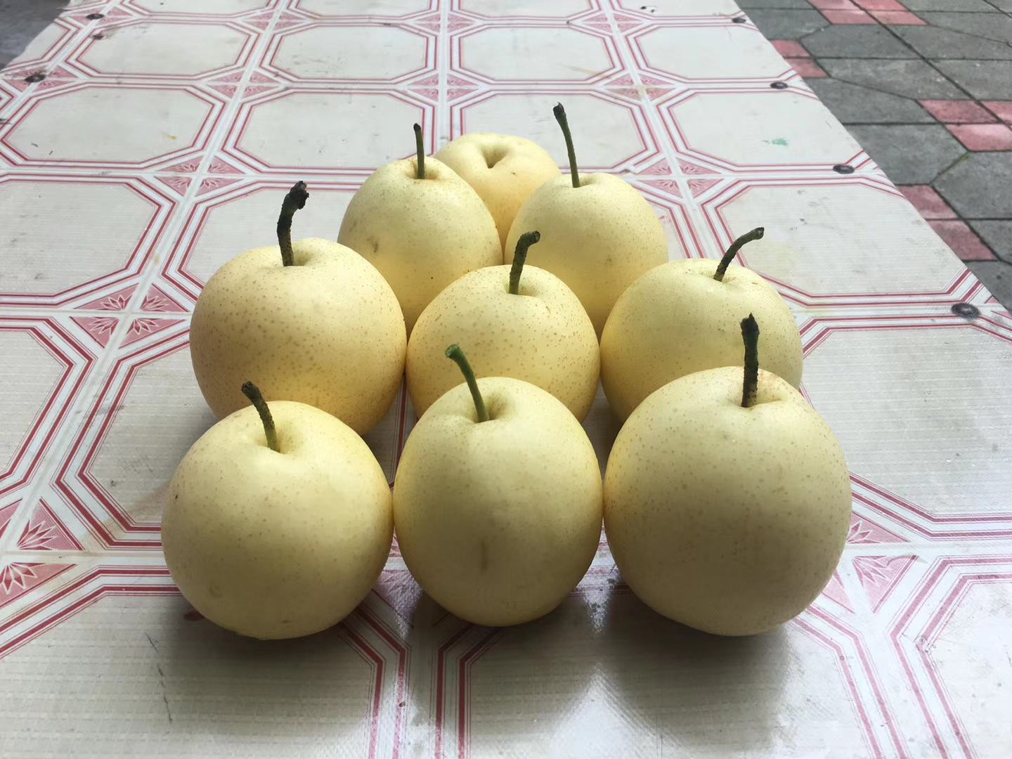 一张高清图片展示多种常见梨的品种,包括鸭梨、雪花梨、香梨和皇冠梨,整齐摆放在木质桌面上,背景为自然光线下的厨房环境,突出水果的新鲜质感和色泽 梨的常见品种展示图