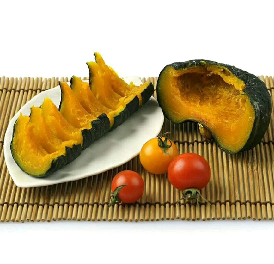 切开的板栗南瓜露出金黄色的厚实果肉,中心有少量种子,果肉纹理细腻,呈现出蒸煮后的柔软质感,背景为白色瓷盘,突出食材本色 板栗南瓜切开内部结构展示