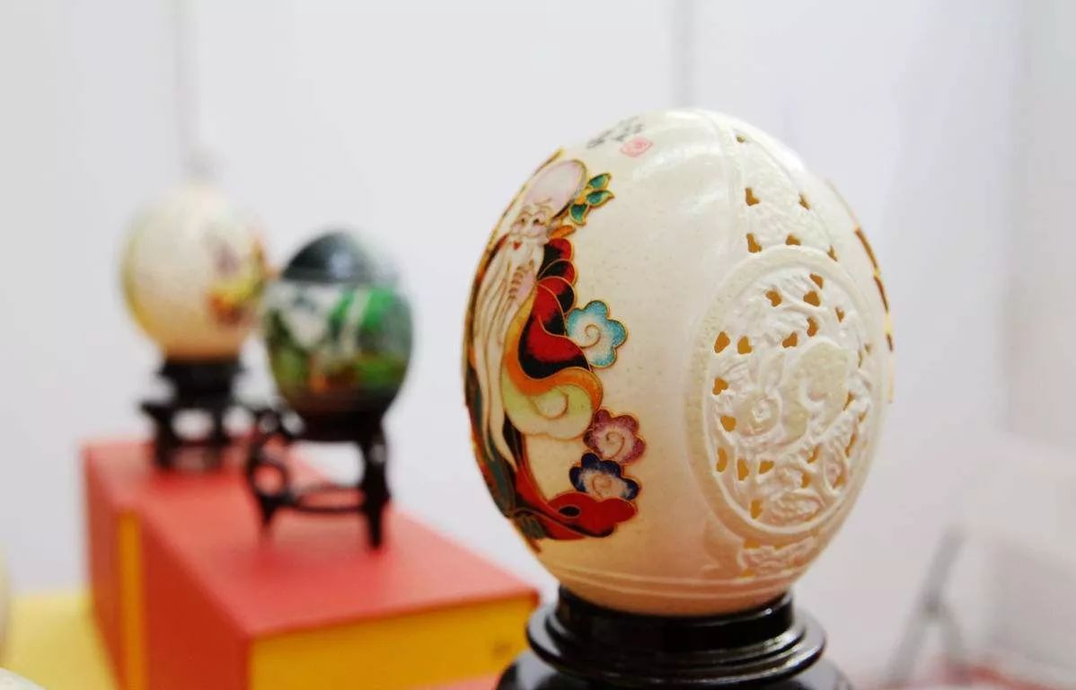 展示多个雕刻精美的驼鸟蛋工艺品,背景为手工艺人正在雕刻 驼鸟蛋文创工艺品展示