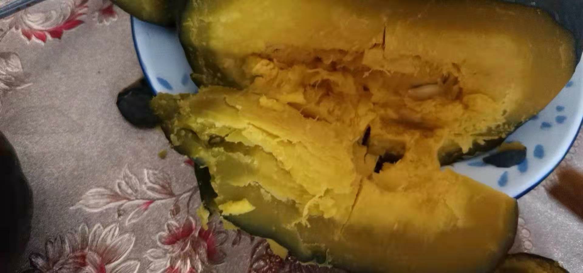 一个新鲜切开的板栗南瓜,露出金黄色的果肉和少量籽,果肉呈现出细腻紧实的质地,颜色温暖如秋日阳光,背景为木质砧板,周围散落着几片南瓜皮 切开的板栗南瓜内部特写