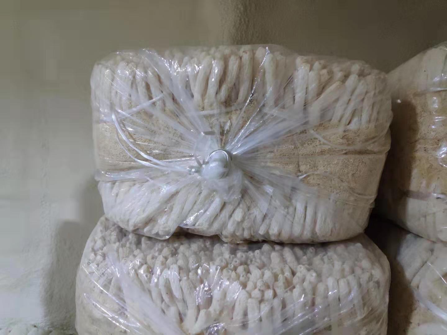 透明塑料密封袋内装有数根完整的干制长裙竹荪,菌裙舒展呈蜂窝状,颜色为象牙白,平铺于木质桌面上,旁边摆放一张带有‘有机认证’标识的标签卡片,背景虚化,突出商品品质与包装规范性 包装精美的长裙竹荪干品展示图