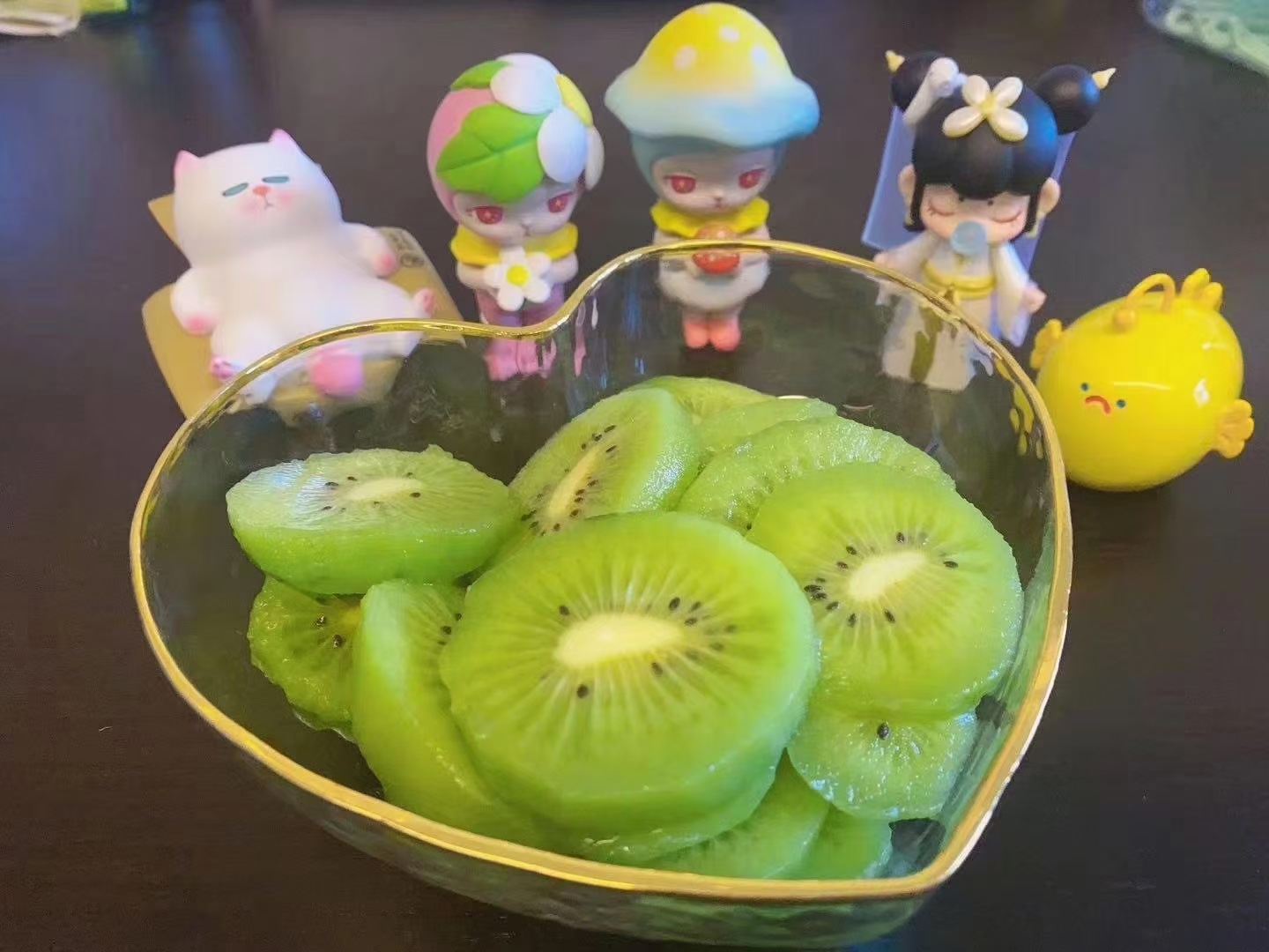 一名约5岁的儿童正开心地咬一口奇异莓,手指捏着果柄,果实完整可见,背景为家庭餐桌,桌上摆放着装满迷你猕猴桃的玻璃碗,阳光透过窗户洒入,营造温馨健康的饮食氛围 儿童手持奇异莓食用场景