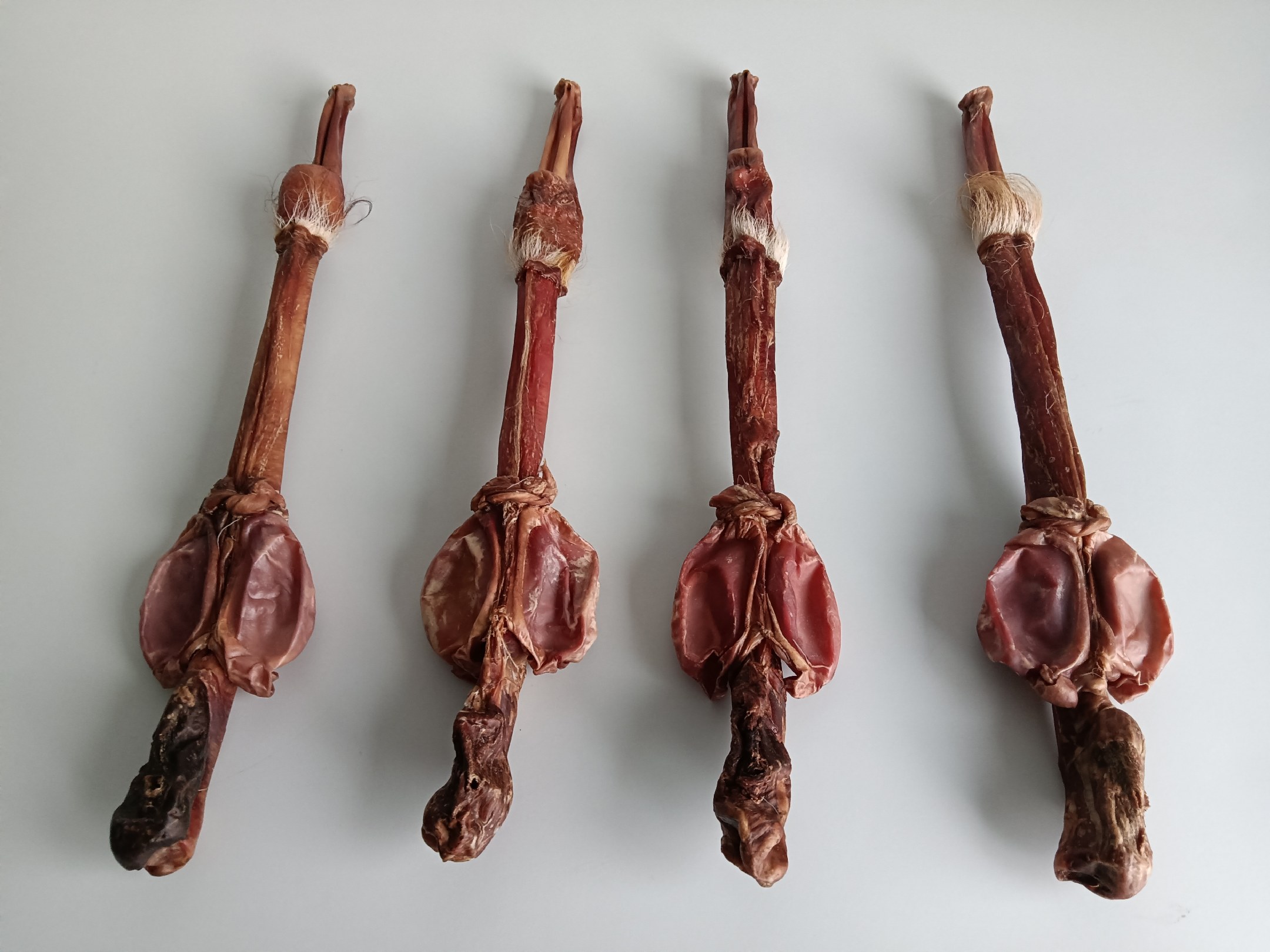 一整根干燥处理后的梅花鹿鞭,呈棕褐色,表面有自然褶皱,质地坚韧,放置于木质托盘上,背景为传统中药柜,体现其作为中药材的专业属性 鹿鞭干品特写