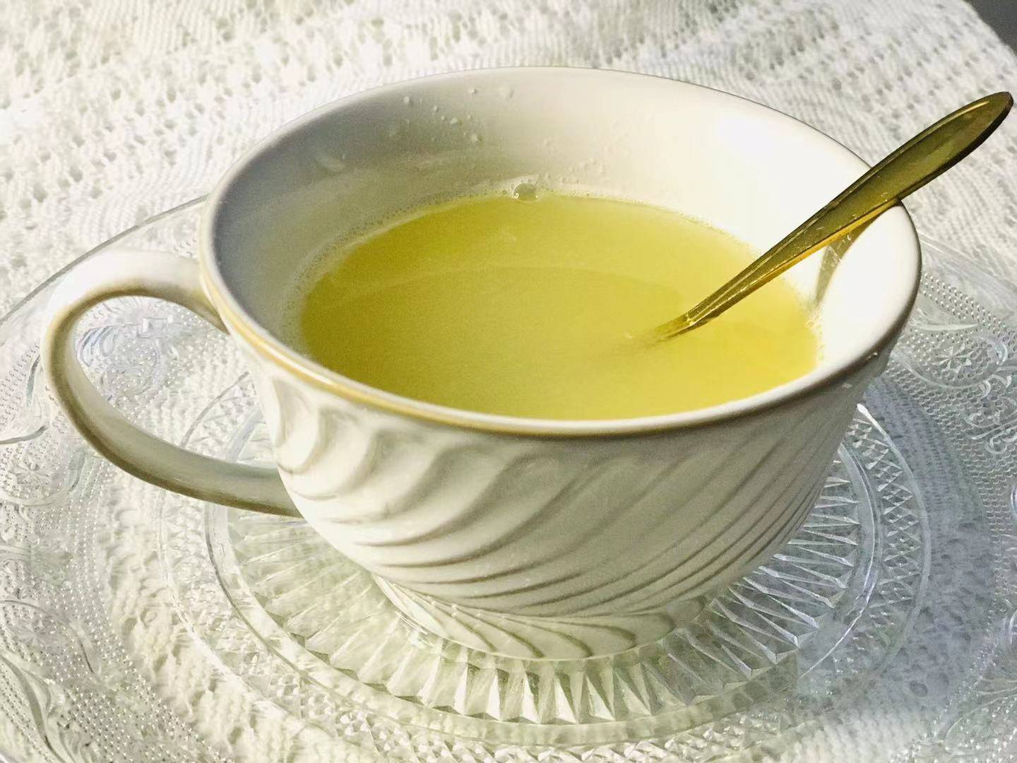 一个透明玻璃广口瓶内盛满粉红色的浓稠柚子茶,果粒清晰可见,瓶身标签写着‘无皮柚子茶’,放置在木质餐桌上,背景有茶杯和柠檬片装饰,阳光洒落营造温馨氛围 玻璃罐中盛放的粉色柚子茶成品