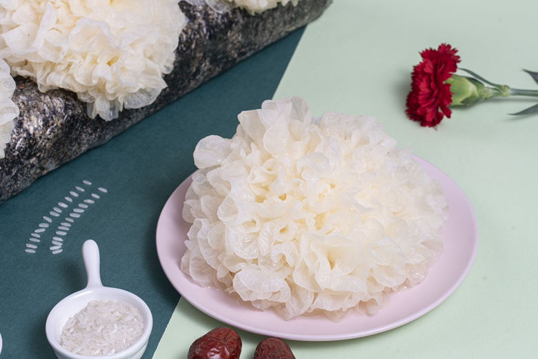 俯拍视角:木质料理台上摆放三组食物场景——左侧为去核长枣夹入核桃仁切片;中为红枣银耳羹盛于青瓷碗中,汤色清亮微稠,浮着几粒完整大红枣枣;右侧为自制红枣山药糕切块,表面嵌半颗完整长枣;所有红枣均为深红饱满、形态修长,无裂纹无杂质,背景柔焦呈现窗边自然光 家庭厨房场景中的大红枣枣创意应用