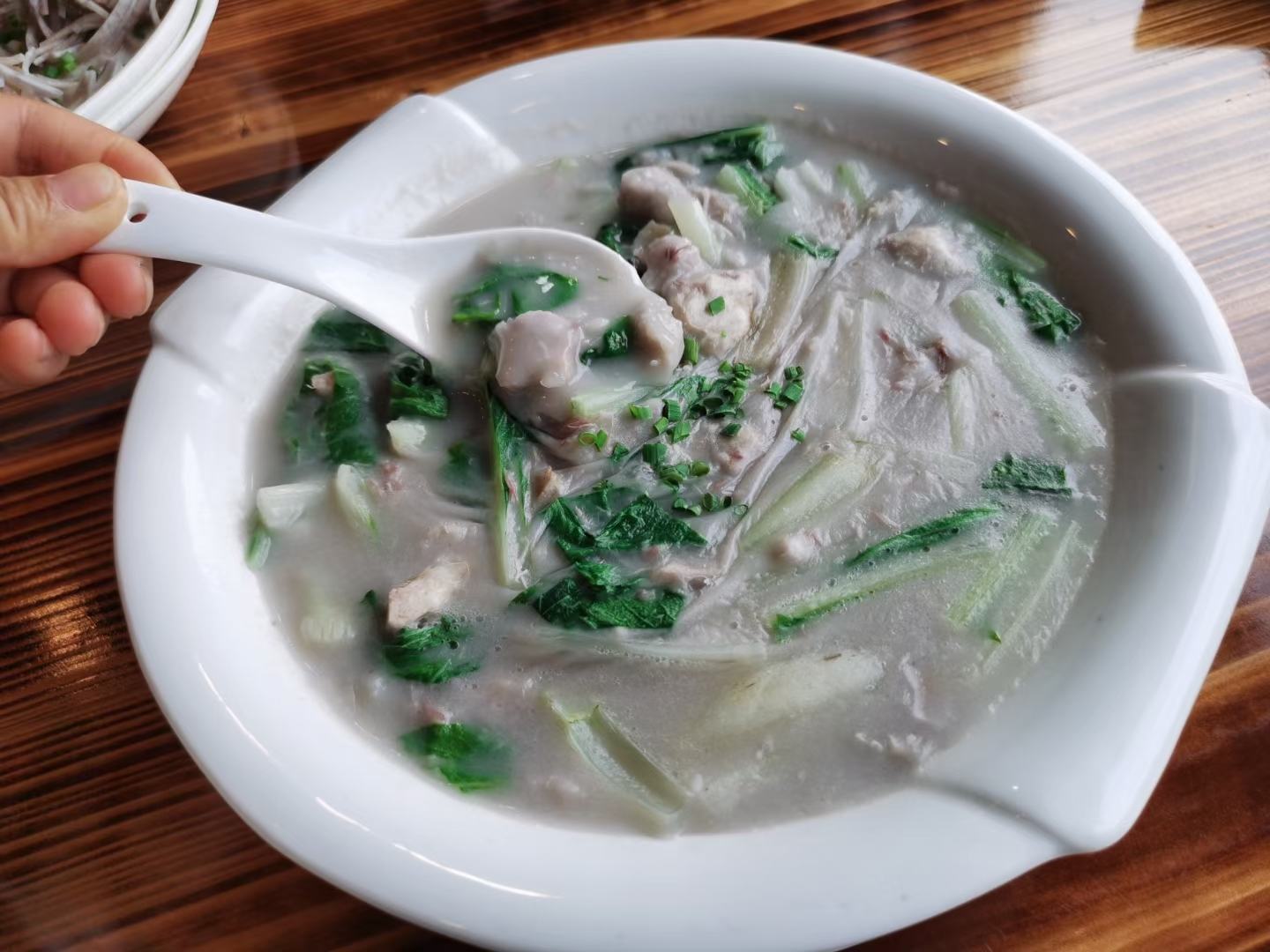 专业美食摄影:晨光氛围下健康早餐组合,荔浦芋头粥表面浮少量米油,蛋清嫩滑无褐变,菠菜翠绿无萎蔫,体现低脂、温热、全营养搭配原则 中式早餐摆盘:青花瓷碗盛放热气氤氲的荔浦芋头粥(米粒分明、芋泥微融),旁配白煮蛋切半、小碟焯水菠菜,整体暖色调,桌面有晨光投影