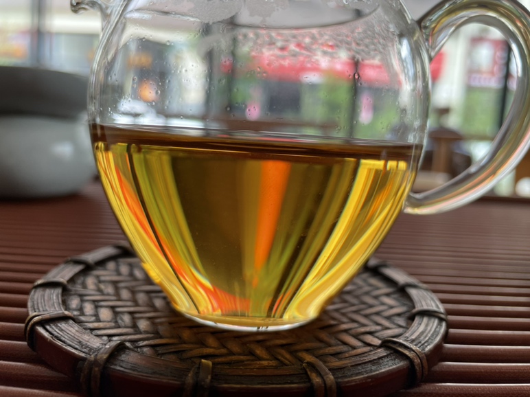 俯拍高清图:琥珀金色茶汤盛于青瓷斗笠杯中,汤面浮着细微姜油光泽;杯旁摆列原生态辅料:古田黑糖砖碎块、新会陈皮丝、三年寿眉茶梗、陈年姜母薄片,背景虚化为闽南红砖厝窗棂,突出‘农产+非遗’双重属性 姜母泡茶成品特写