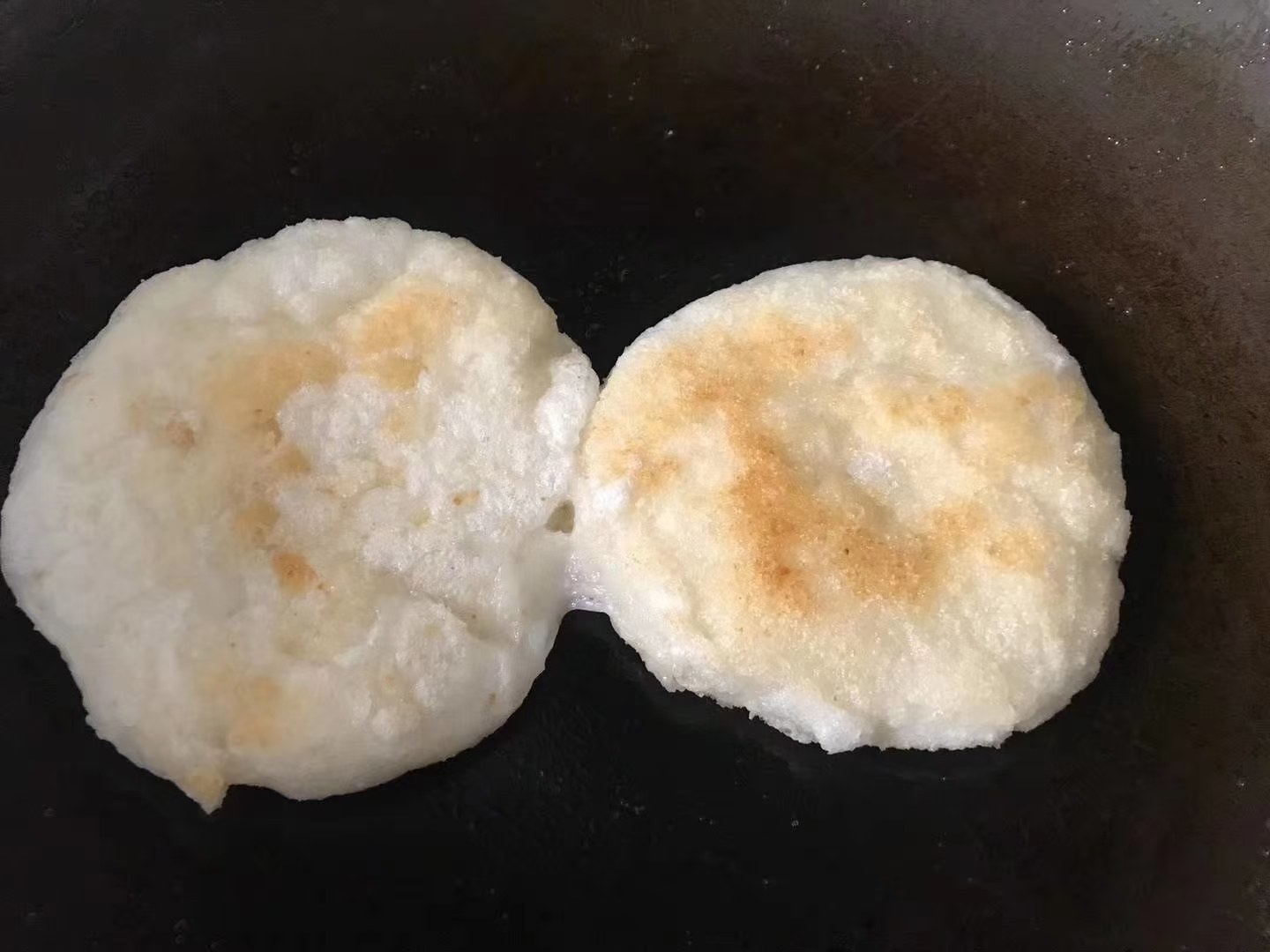 煎制中的水果玉米粑粑特写：琥珀色焦脆外皮包裹金黄柔韧内芯，平底锅中滋滋作响，边缘微翘起，散发焦糖与玉米复合香气
