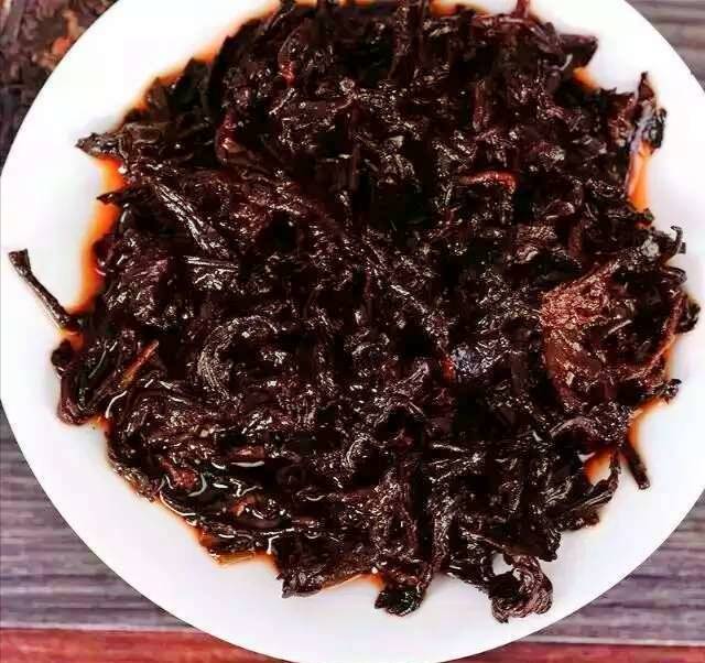 图片说明:熟地黄与炒白术泡出的茶汤呈琥珀色,清澈透亮,旁边配有量勺和中药材标签,体现科学养生理念 熟地黄与炒白术搭配泡茶的成品图