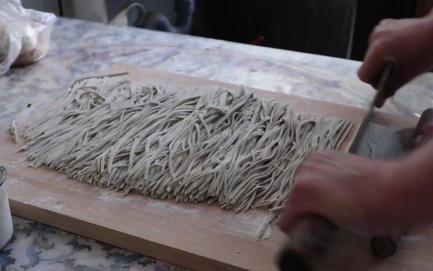 削面过程展示，手持削面刀正在削出面条
