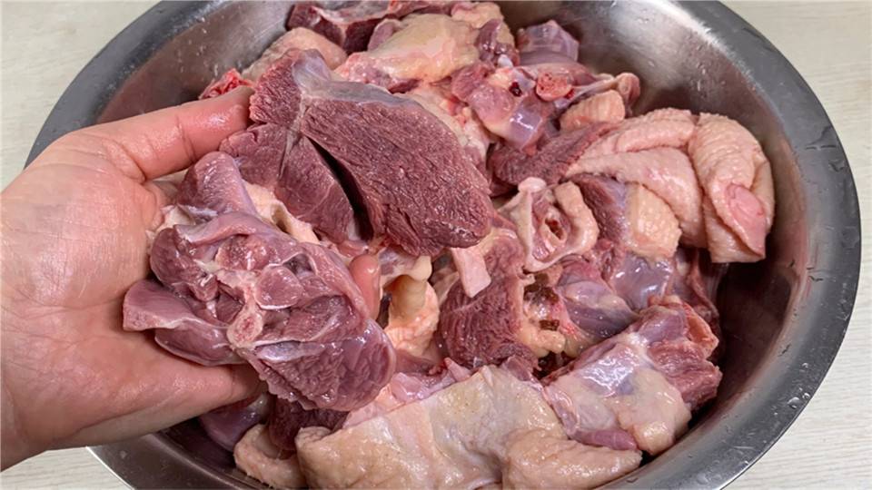 鹅肉焯水过程,锅中翻滚的鹅肉块,旁边摆放着生姜和料酒 鹅肉焯水过程