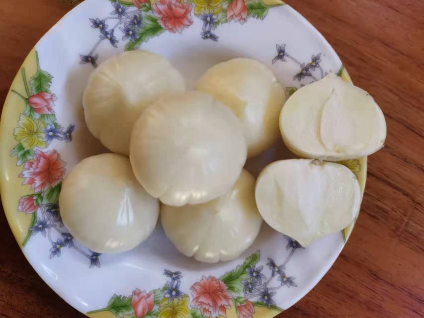 透明玻璃罐中浸泡着乳白色独头蒜，液体清澈微黄，蒜瓣饱满晶莹，瓶身有轻微冷凝水珠