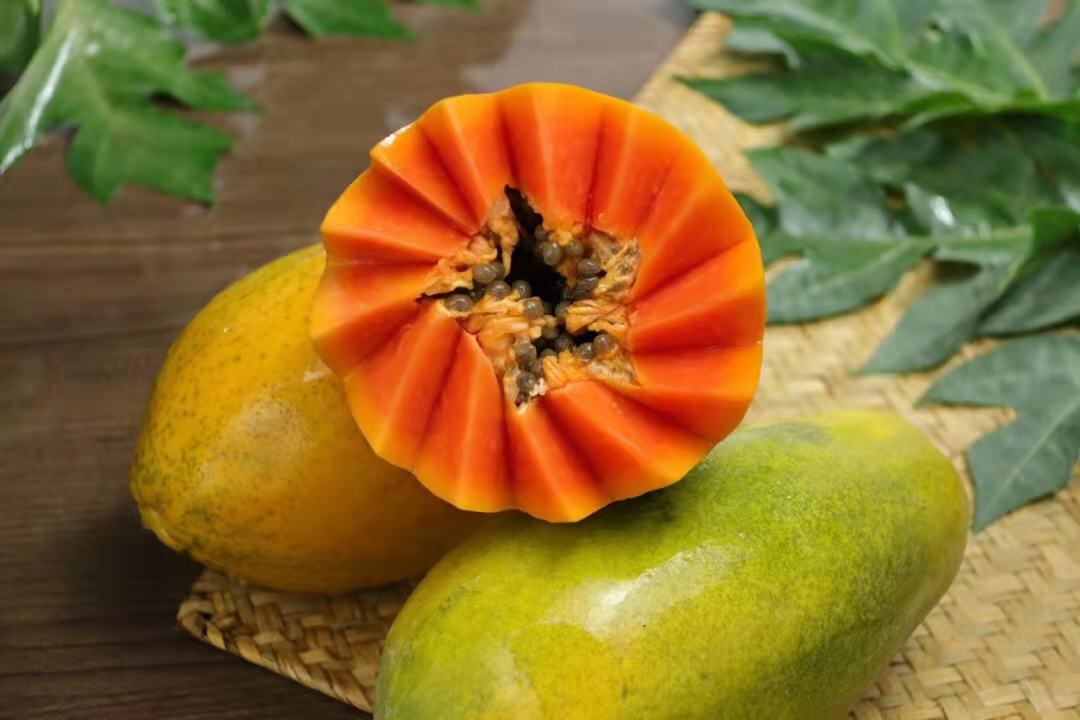 剖开的成熟木瓜，内部可见一个较小的完整木瓜状结构，周围为橙红色果肉，种子排列清晰