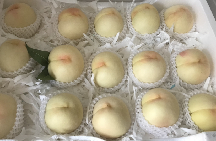 一张展示桌上摆放多种平顶突围桃的包装形式:透明塑料盒装精品果、纸质礼盒、网袋家庭装,旁边配有二维码标签和品牌LOGO,背景为快递打包台,体现从生产到销售的完整链条 包装与销售渠道展示图