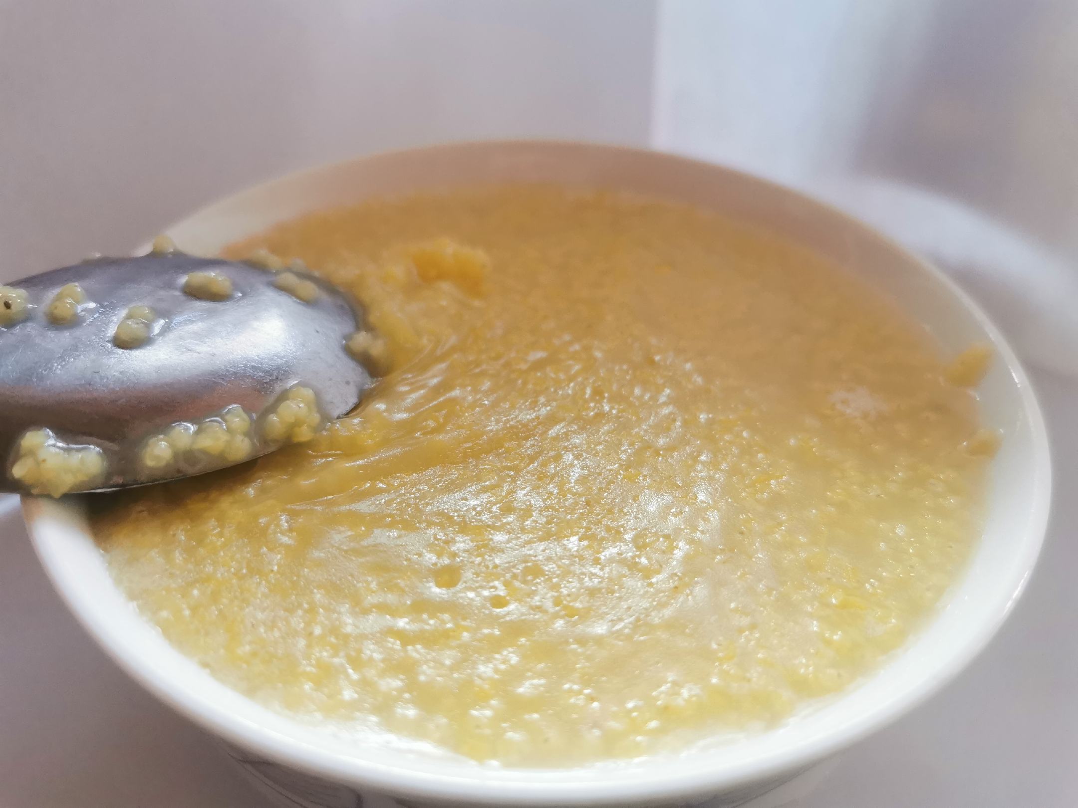 一碗热气腾腾的甜瓜山药小米粥,呈淡黄色,质地细腻 甜瓜山药小米粥成品图