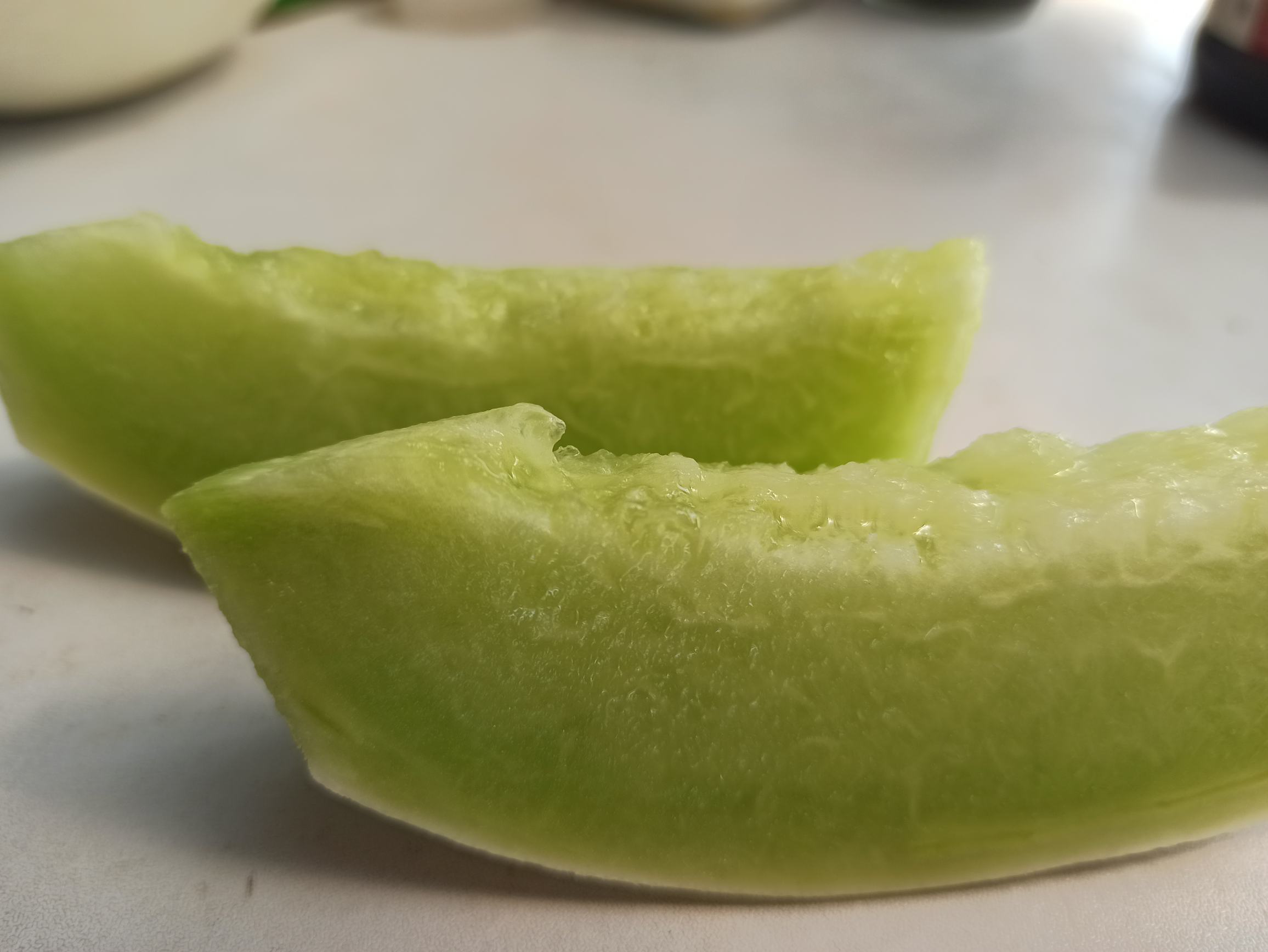 两个切开的甜瓜并排放置在白色瓷盘中,左侧为玉菇甜瓜,果肉洁白透明,结构紧实;右侧为奶香蜜甜瓜,果肉呈乳白色,略显油润光泽,中心柱稍宽。背景虚化,突出果实内部细节,用于展示肉色、腔室大小及汁液分布 切开的玉菇甜瓜与奶香蜜甜瓜横截面对比图