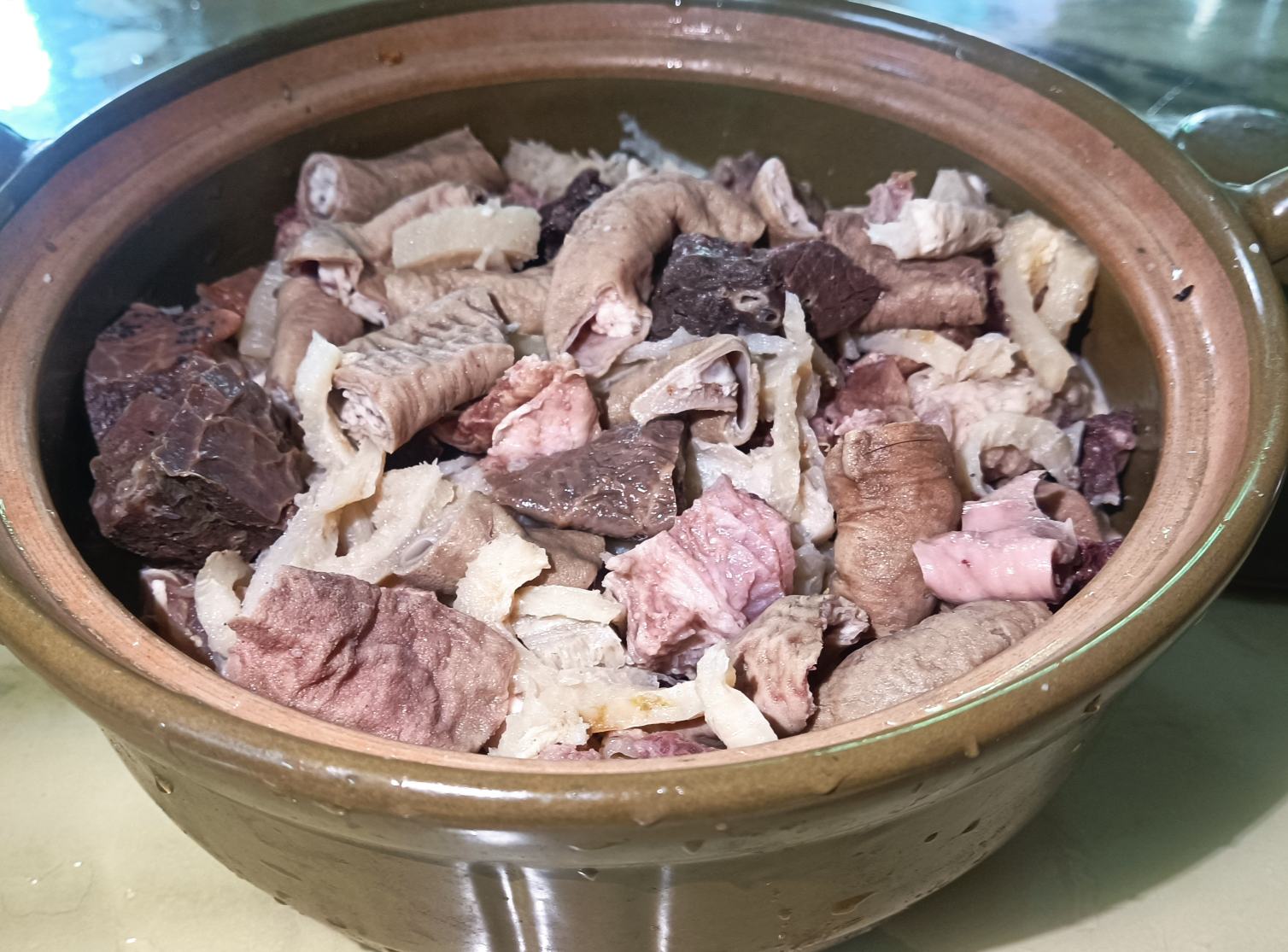 家庭厨房去内脏操作特写,展示不锈钢镊子夹取完整消化腺过程,强调工具材质(非铁质)与内脏颜色形态特征,光线充足、无阴影干扰 家庭厨房操作实景:左手持半开蛤壳,右手用不锈钢镊子精准夹取深褐色消化腺,内脏已完全离体,露出粉白色闭壳肌与浅黄生殖腺,背景为木质砧板与不锈钢盆