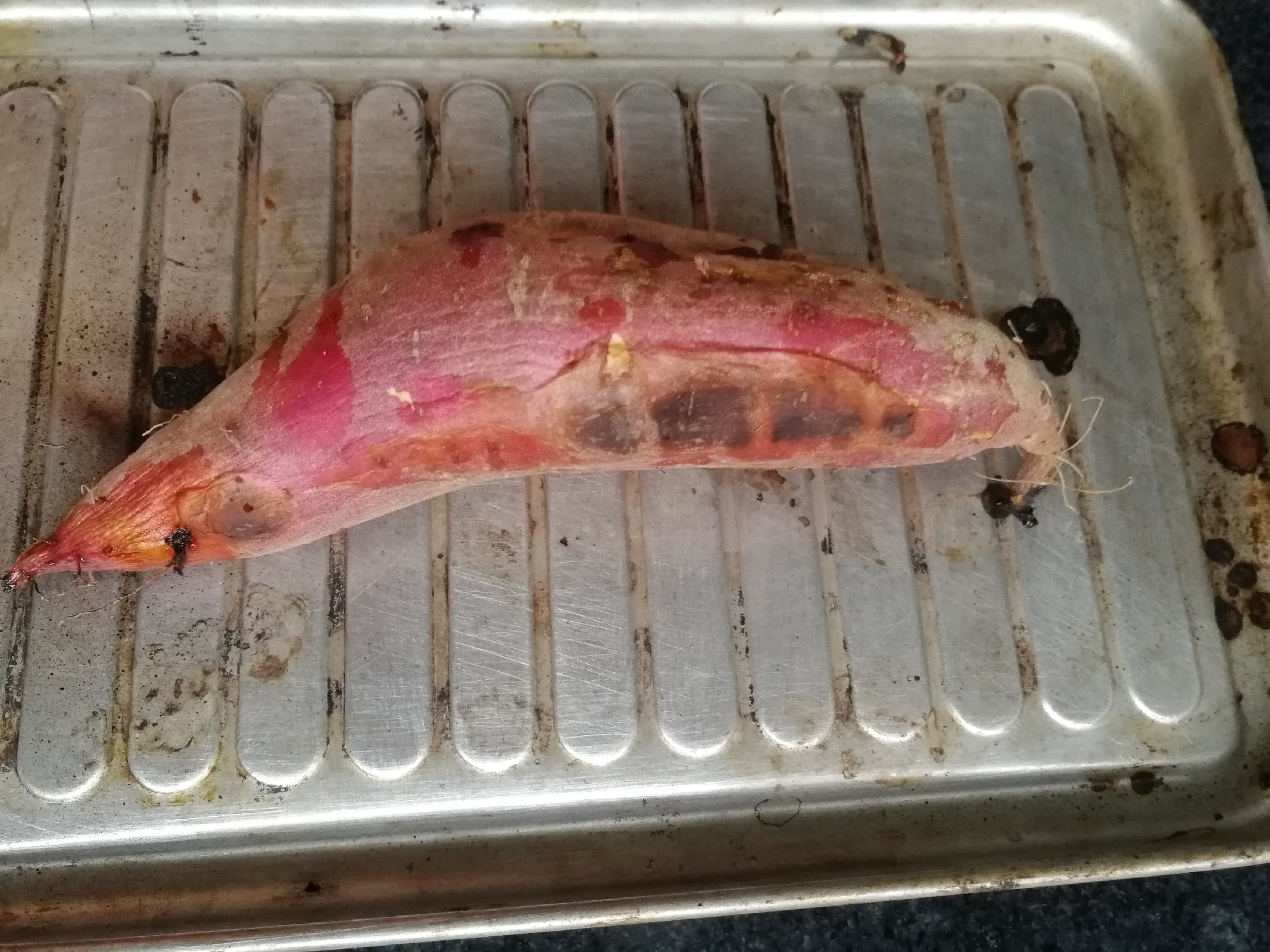 家庭烹饪场景展示济薯26地瓜的常见做法——烤制,同时通过剖面呈现其标志性的橙黄薯肉色泽 一位家庭主妇正在厨房用锡纸包裹济薯26地瓜准备放入烤箱,操作台上有切开的生薯块展示内部橙黄色的薯肉