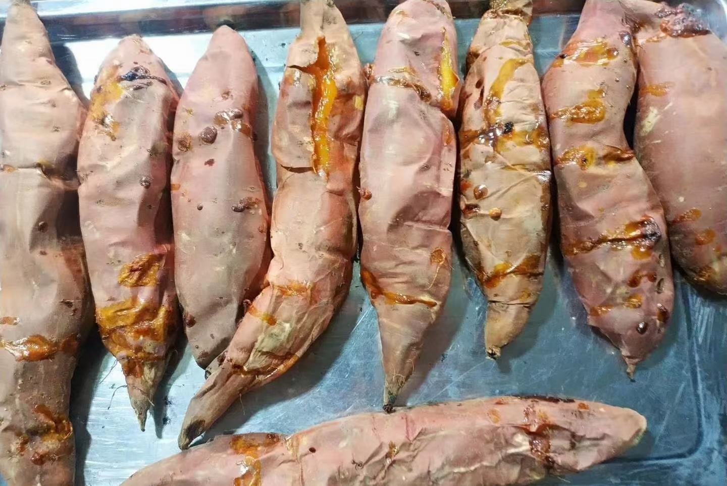 专业美食摄影:烟薯25号烤制中段(约45分钟)状态,剖面朝上置于黑曜石烤盘,薯肉中心温度计显示82℃,表面覆盖一层透亮琥珀色焦糖膜(厚度约0.3mm),边缘出现自然卷曲焦边,无任何汁液渗出或塌陷,蒸汽呈稳定柱状上升 烟薯25号烤制过程特写:剖开的半只烟薯置于预热至200℃的石板上,金橙色薯肉表面已形成薄脆糖壳,边缘微焦卷曲,内部蒸汽氤氲,无汁液外溢