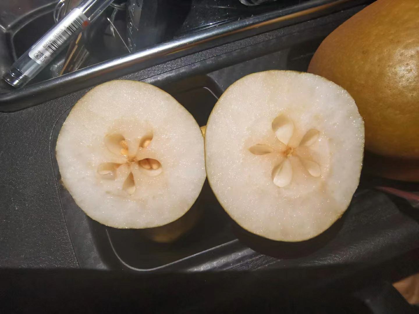 剖开的巴梨横截面,露出乳白色细腻果肉,中心可见黑色种子排列成心形结构,背景为浅色厨房台面,强调其可食用性和内部结构特征 巴梨切面展示果肉质地