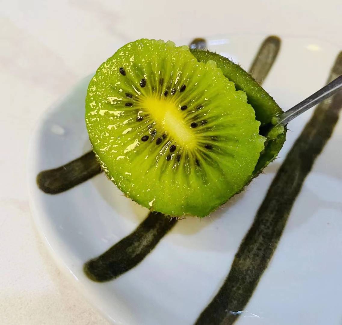 切开的翠香猕猴桃特写，果肉呈鲜艳的翡翠绿色，汁水丰盈，旁边摆放一把测糖仪显示糖度读数为18.5%