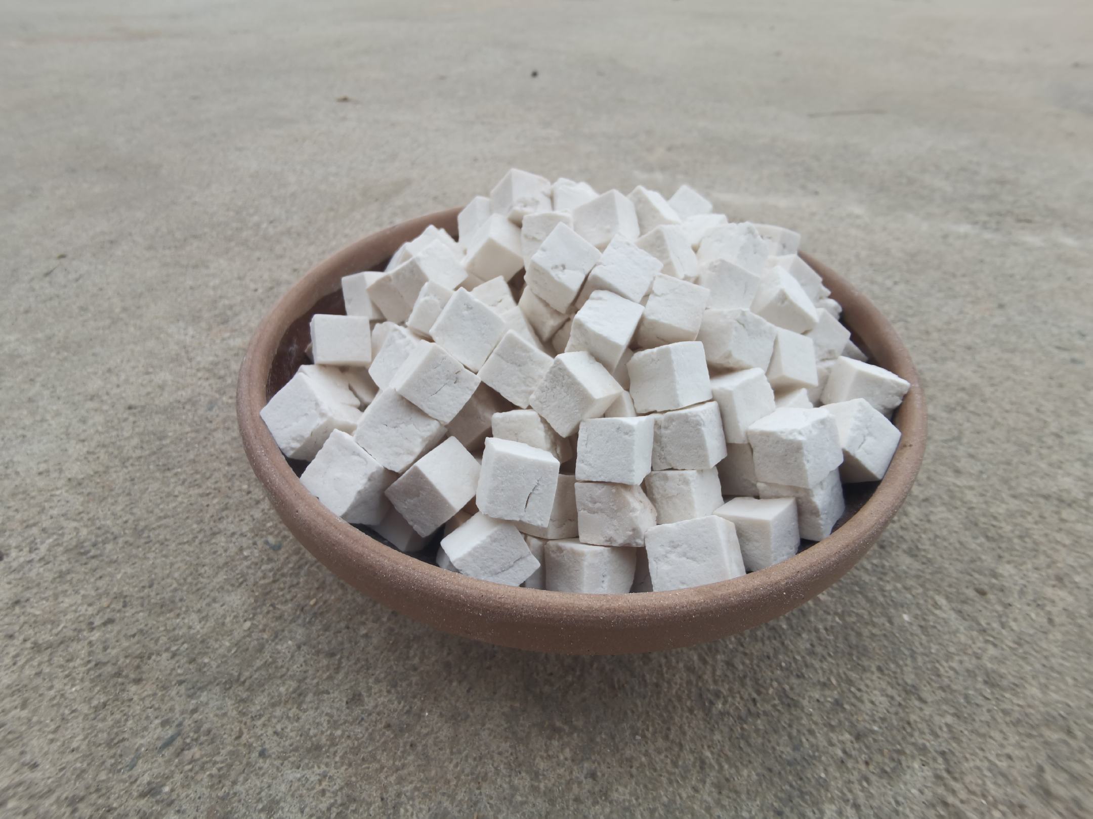 图中展示一碗热腾腾的白术茯苓粥,旁边摆放着白术片和茯苓的原料 白术茯苓粥成品图