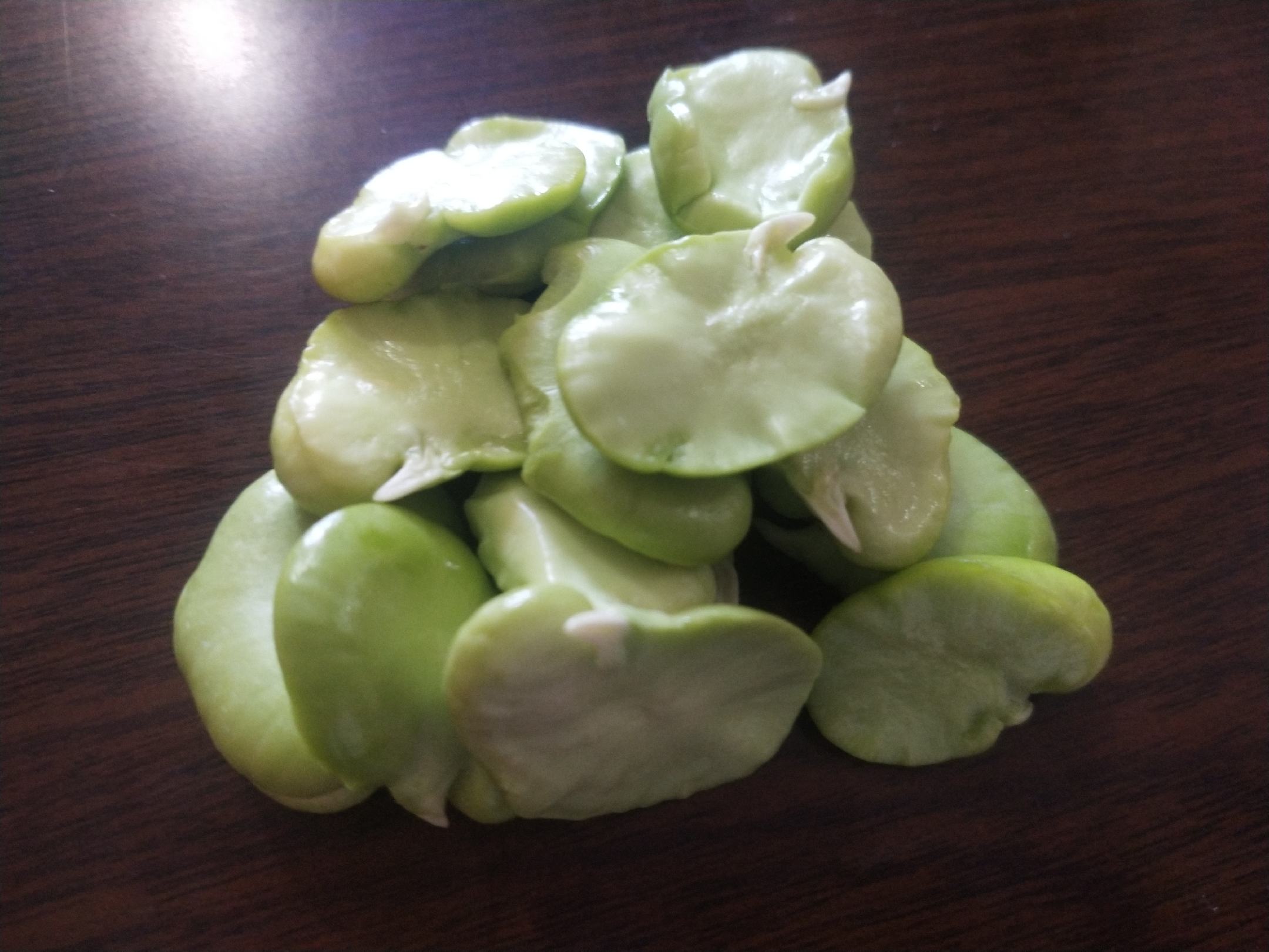 木质砧板上分别摆放着剥好的绿色豌豆粒和去壳的淡黄色蚕豆仁,旁边有不锈钢锅具和香料,模拟家庭厨房准备食材的温馨场景,突出两种豆类在烹饪中的应用差异 厨房中豌豆与蚕豆的烹饪场景