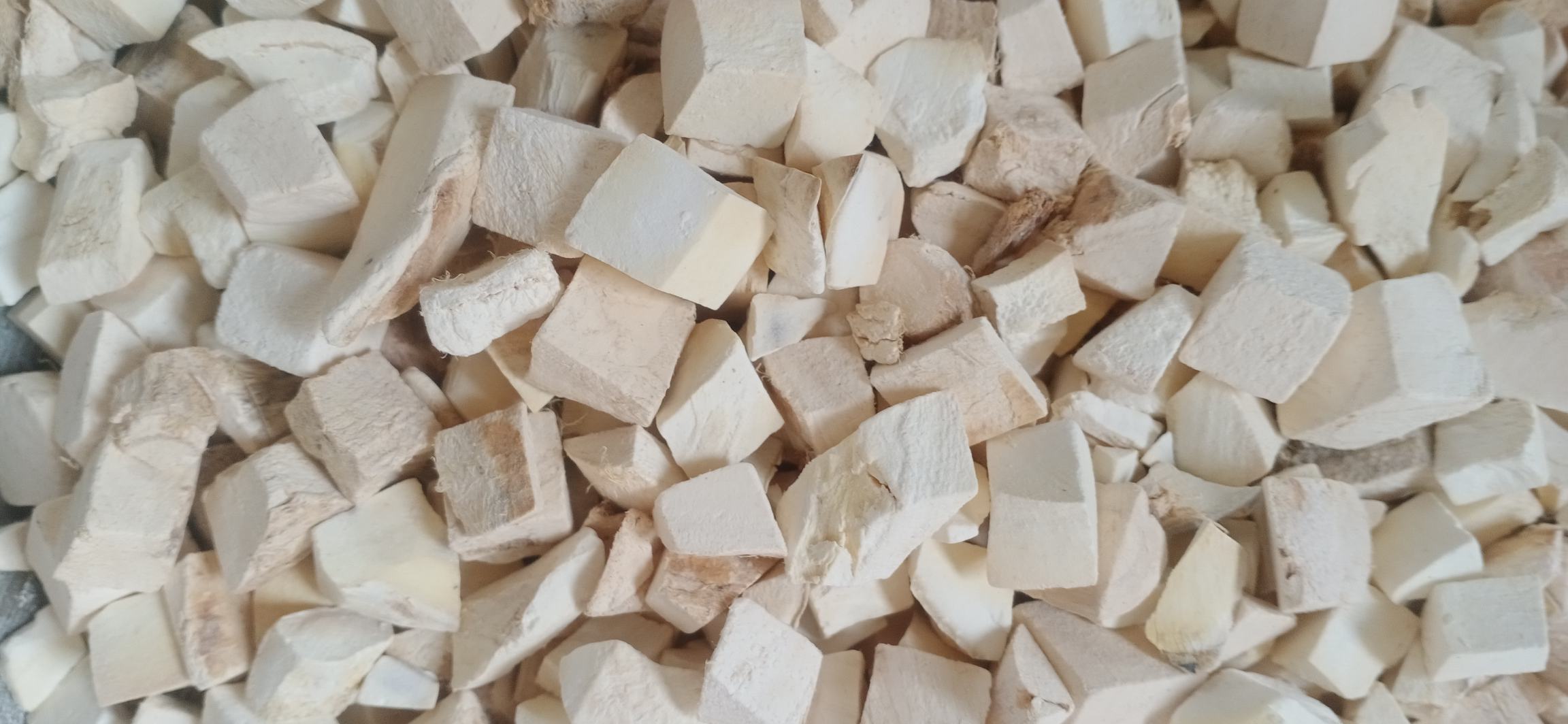 新鲜粉葛块根与干燥切片并列展示,左侧为带皮土黄色块状根茎,表面粗糙有须根痕迹;右侧为淡黄色薄片,质地均匀,呈半透明状,背景为木质砧板和陶瓷碗,体现家庭烹饪场景 粉葛切片与新鲜块根对比图