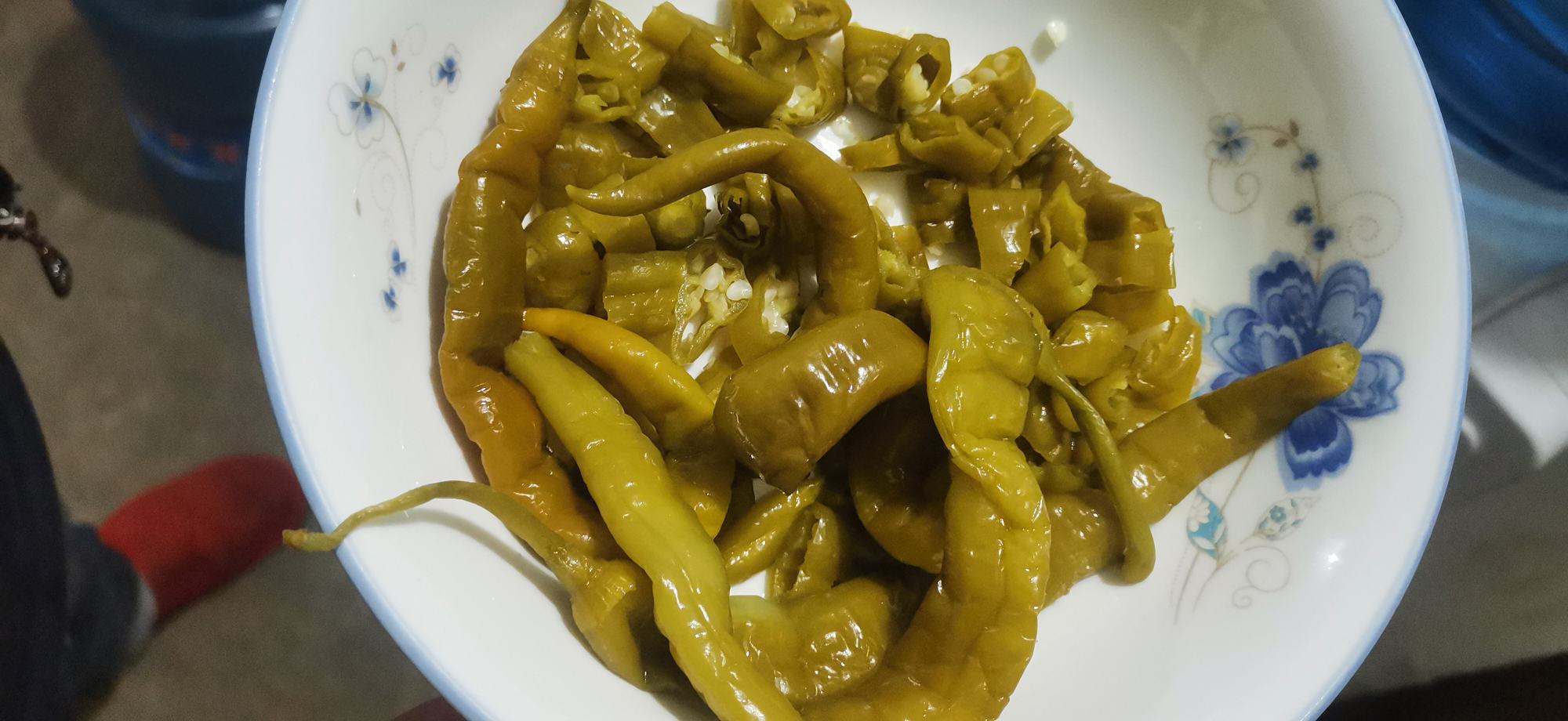 一个传统的陶瓷泡菜坛子,内部可见辣椒正在泡菜水中慢慢发酵,周围摆放着厨房用品 泡椒发酵过程示意图