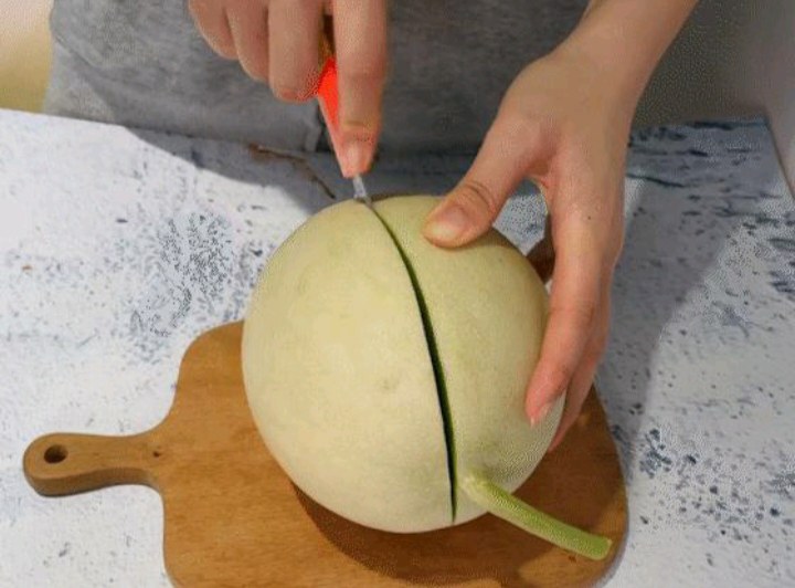 女性正在切玉菇甜瓜，准备制作水果沙拉