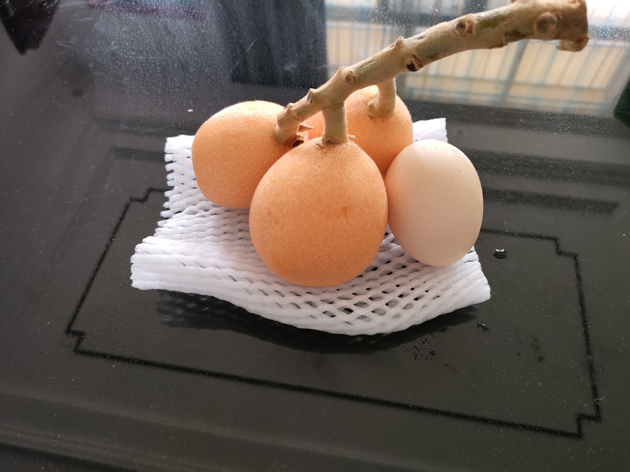 卧室床头柜上放置一碗剥好切片的枇杷果肉,旁边是一本打开的书和一杯温水 夜晚床头放着一碗枇杷果肉