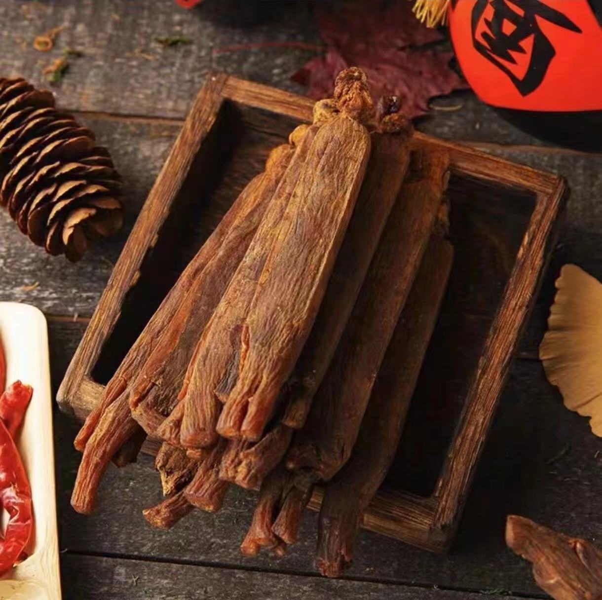 一盘浅黄色的花旗参薄片整齐摆放在白色瓷碟中,背景为木质茶几,旁边配有透明玻璃密封罐和干燥剂包,展示家庭常见保存场景 花旗参片实物图