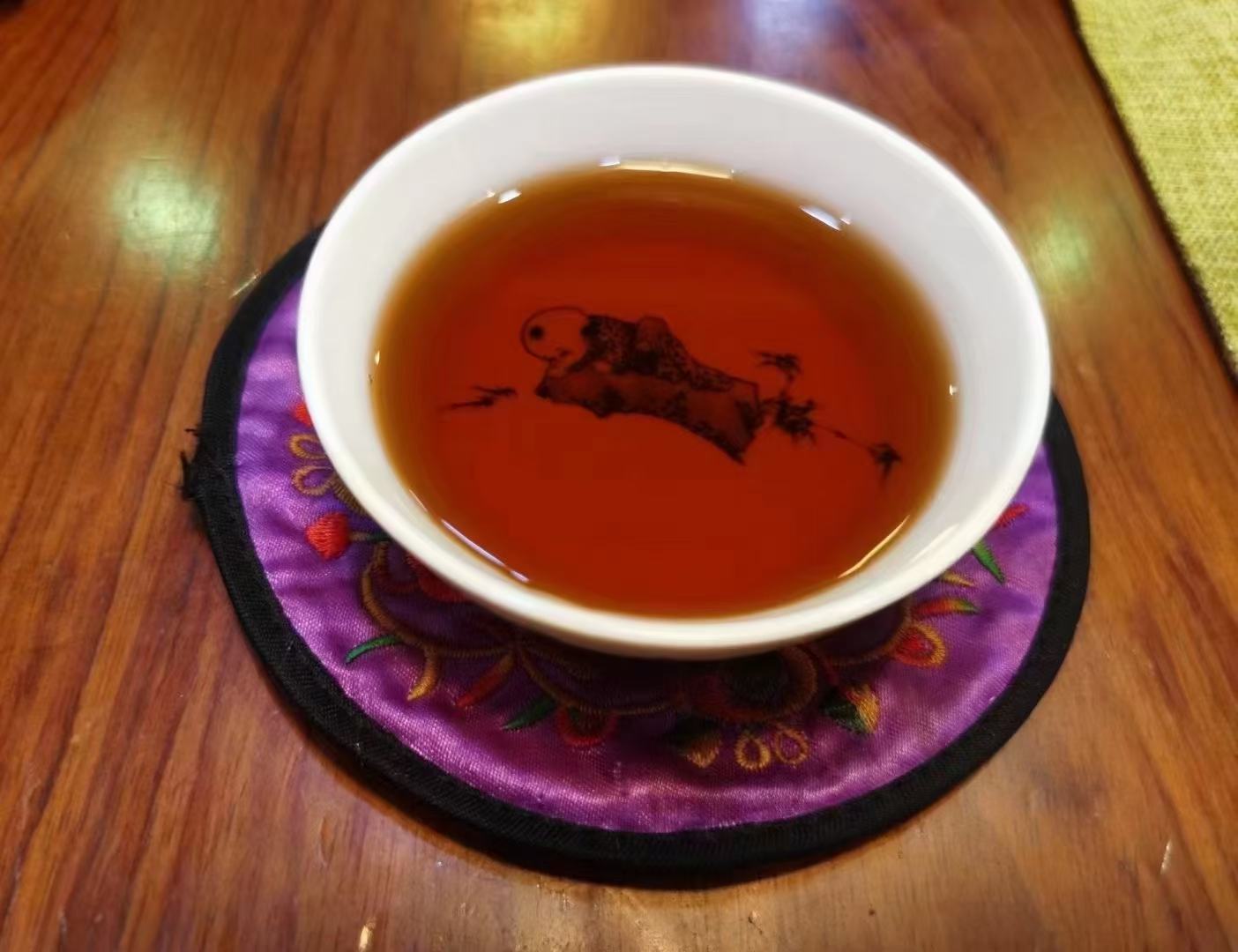 茶艺师手持白瓷盖碗冲泡妃子笑茶：身着素雅蓝染棉麻茶服，手势娴熟行‘关公巡城’，热气氤氲中可见金黄茶汤注入小杯，背景为原木茶席与凤凰单丛茶饼礼盒，整体构图体现人文温度与产品价值