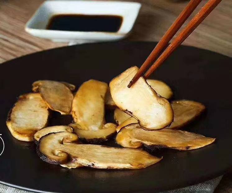 一道精致的西式摆盘菜肴,主料为黄油煎制的松茸片,表面微焦金黄,散发油光,搭配迷迭香和樱桃番茄点缀,盘边有酱汁勾勒,展现高级餐厅级的烹饪水准 松茸料理成品图